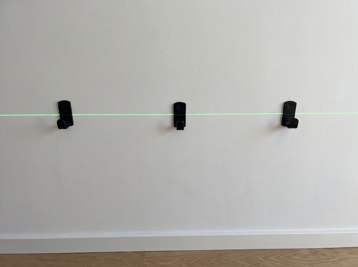 Dieselben drei Haken auf einer Linie entlang der grünen Laserlinie